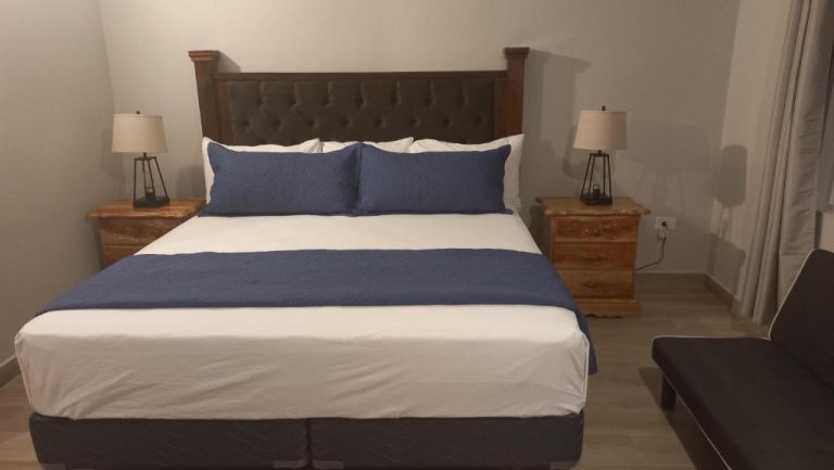 Habitación con cama king size y cabecero de madera en Beach Studio 20, decorada en azul y blanco