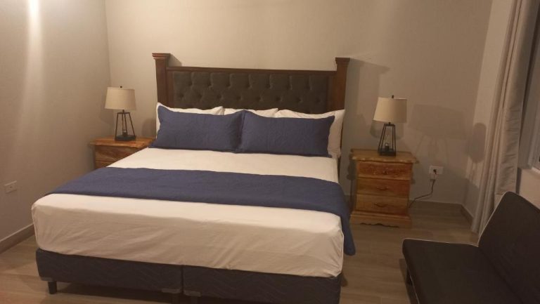 Habitación con cama king size y cabecero tapizado en Beach Studio 20, decorada en tonos azules y blancos