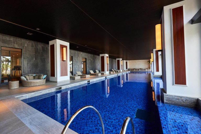 Piscina interior climatizada con tumbonas y decoración elegante en Ryukyu Hotel Resort Nashiro Beach