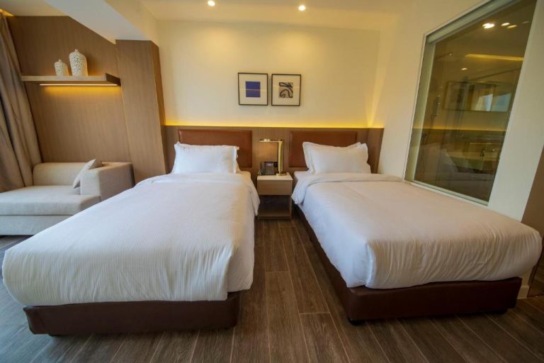 Habitación doble twin con dos camas individuales y baño acristalado en Luxotel Aqaba Beach Resort & Spa