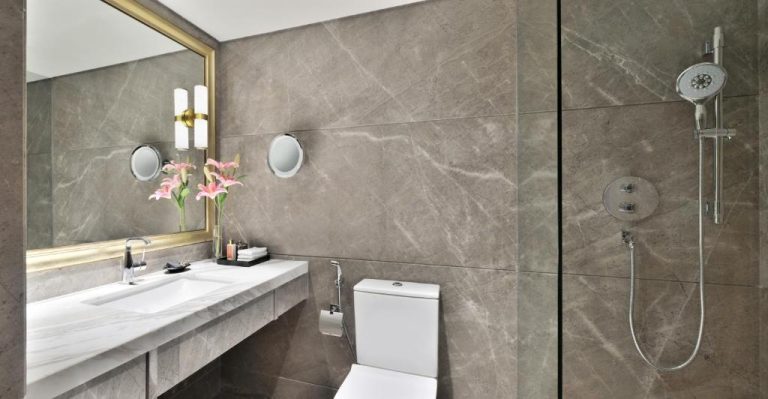 Baño de lujo con mármol gris, ducha y lavabo del hotel Taj Mahal New Delhi