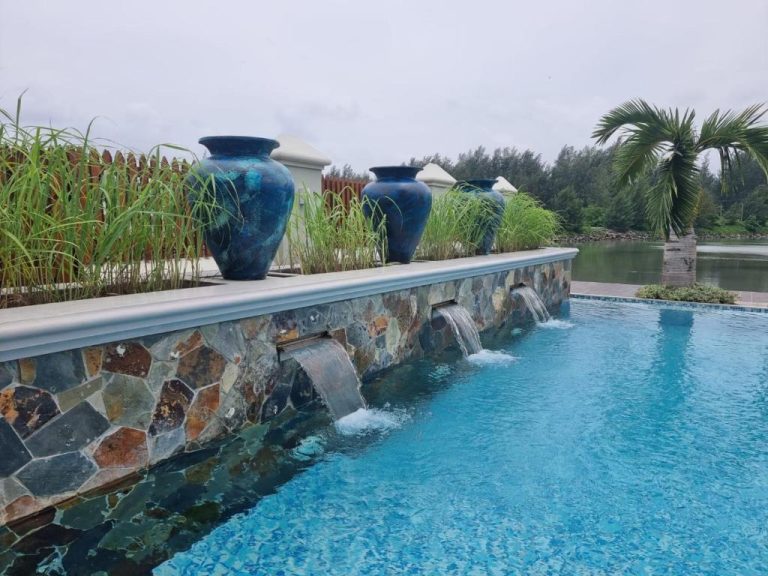 Piscina exterior con cascadas de agua y jarrones cerámicos azules en Phoenix Apartments