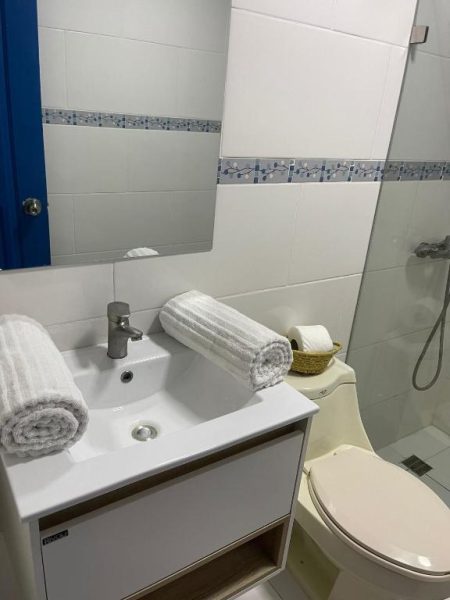Baño privado moderno con ducha, lavabo y toallas blancas en Nuovo Hotel Playa Catalina