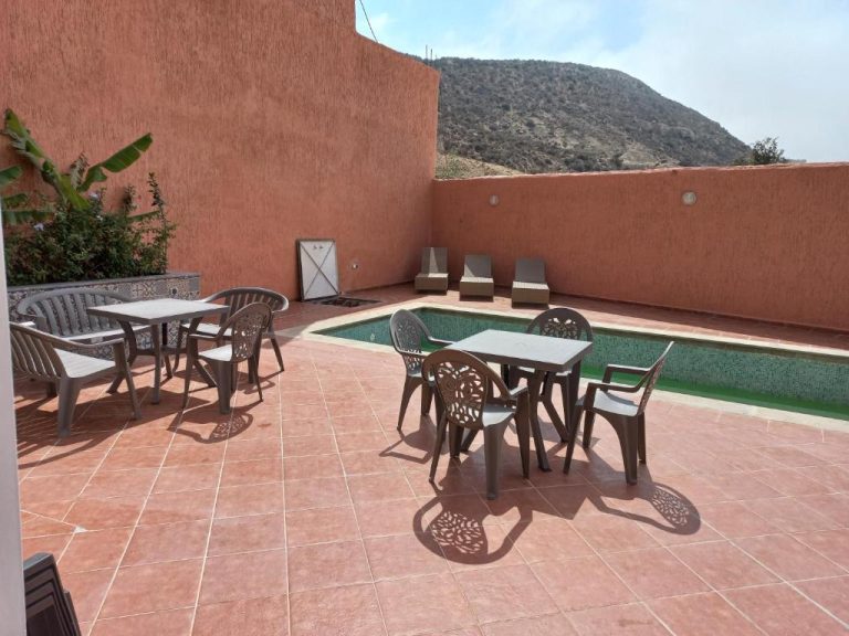 Terraza con piscina exterior y mesas del BananaHouse con vistas a la montaña