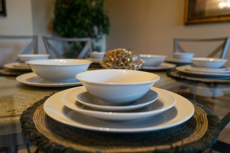 Mesa del comedor del Hotel Pura Vida con vajilla blanca apilada sobre individuales de fibra natural