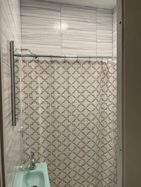 Baño con ducha y cortina decorativa de arabescos en Navona Studios, con azulejos modernos en gris
