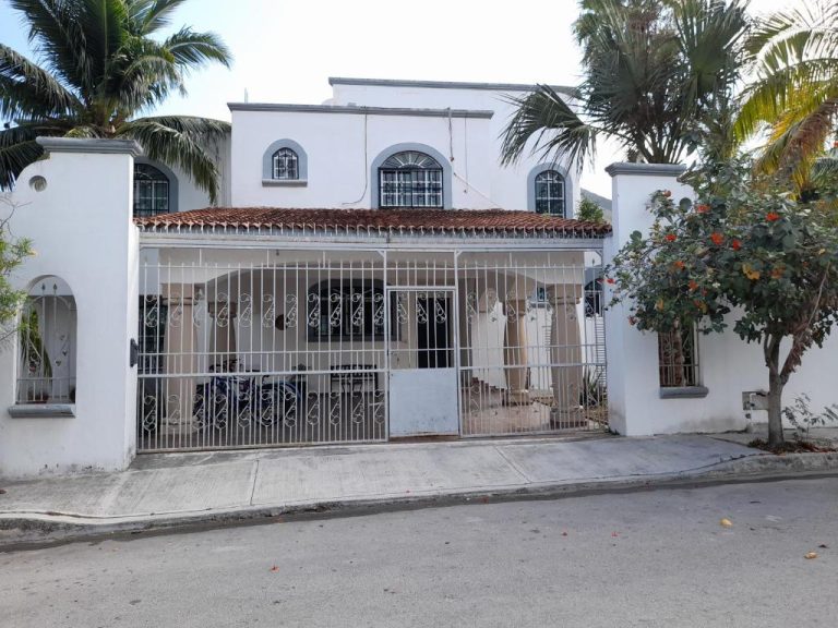 Fachada exterior del Hotel Claro de Luna con portón de hierro forjado y palmeras tropicales