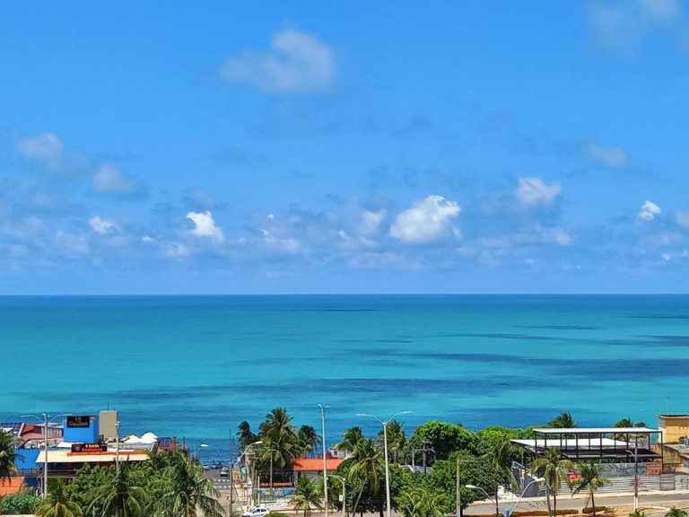 Vista panorámica al mar turquesa desde Ilusion Flats Aconchego de Ponta Negra con palmeras y paseo marítimo