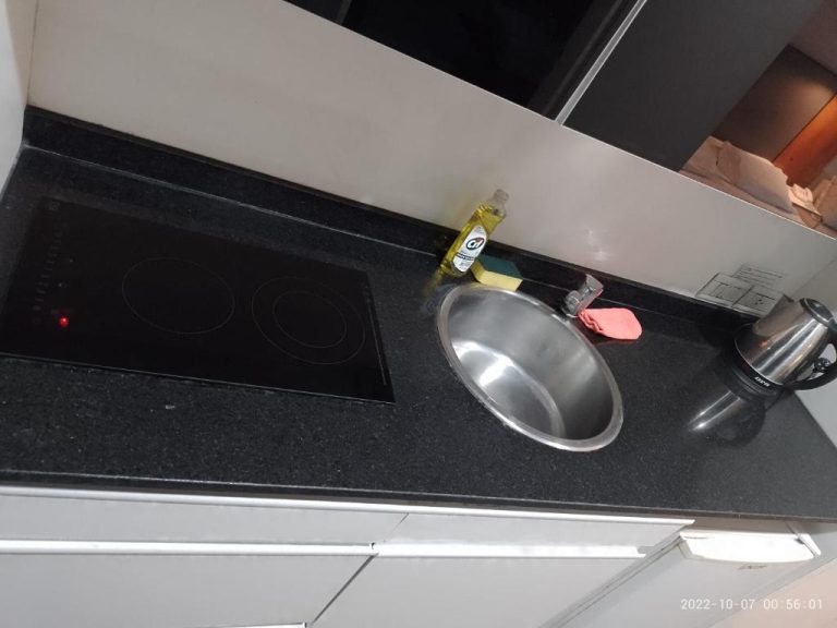 Cocina compacta con vitrocerámica, fregadero de acero y hervidor en Buenos Aires Apartamento