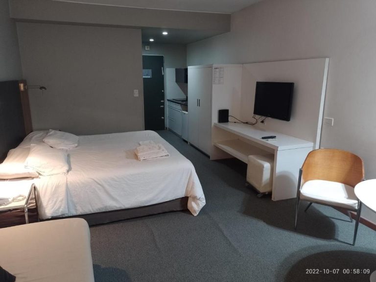 Habitación estudio con cama doble, escritorio, TV y cocina integrada en Buenos Aires Apartamento
