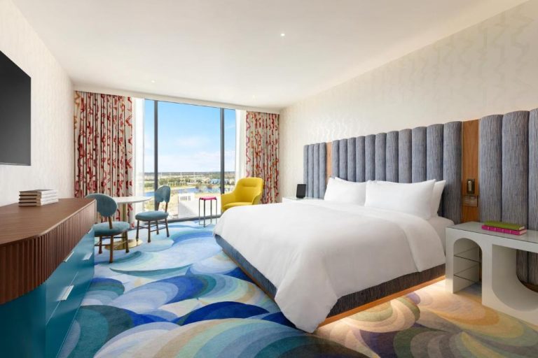 Habitación king con cabecero tapizado, alfombra artística y vista al lago en Lake Nona Wave Hotel
