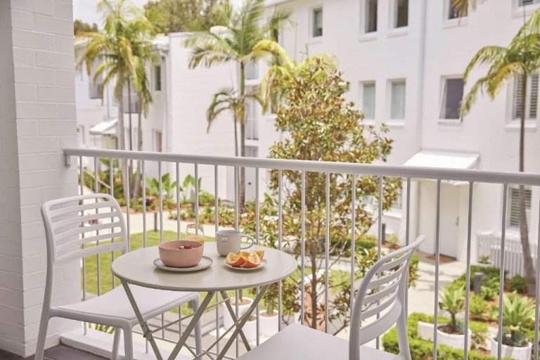 Terraza privada con mesa y sillas blancas y desayuno en Adina Apartment Hotel Chippendale