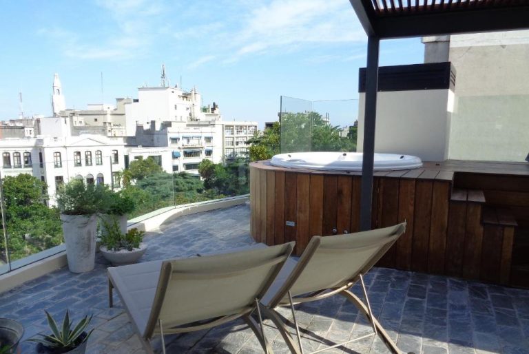 Terraza exterior con jacuzzi de madera y tumbonas con vistas a la ciudad en Alma Histórica Boutique Hotel