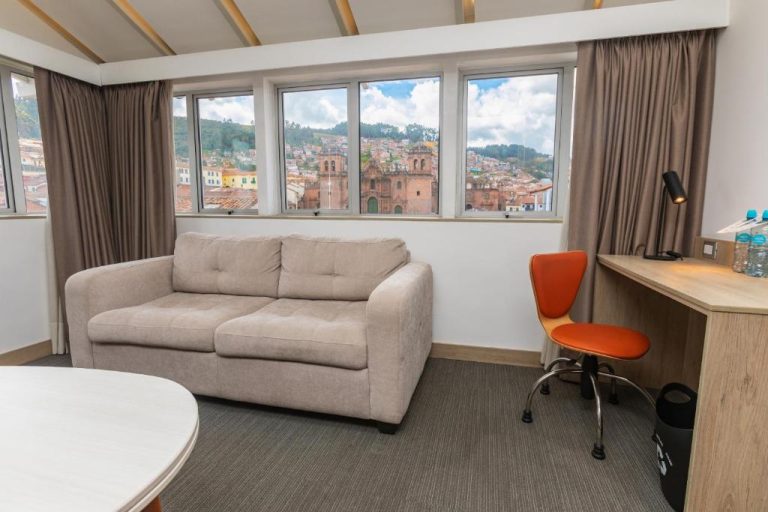 Habitación con sofá y escritorio con vistas a la catedral del Cusco en Casa Andina Standard Cusco Plaza
