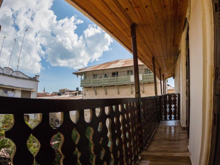 Balcón colonial con barandilla de madera tallada y vistas a la ciudad en el hotel Aurelia Zanzibar