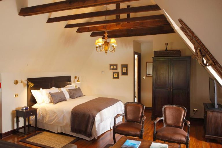 Habitación con vigas de madera y decoración colonial en Hotel Boutique Castillo Rojo