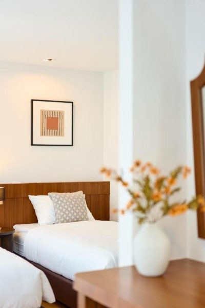 Habitación twin con cabecero de madera y decoración minimalista en Be Phrasingh Hotel Chiang Mai