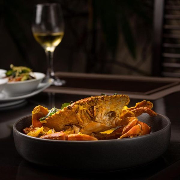 Plato de cangrejo al curry servido en el restaurante del Terrace Green Hotel and Spa con copa de vino blanco