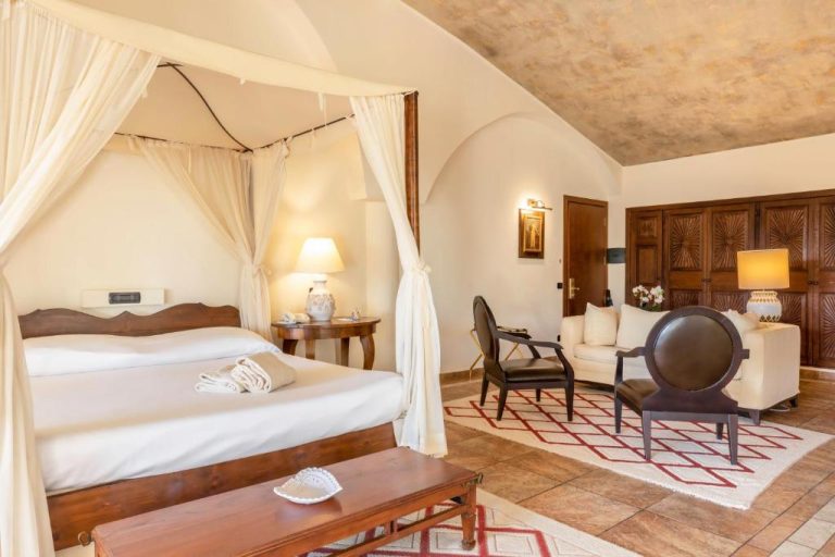Habitación de lujo con cama dosel y sala de estar elegante en Hotel Costa dei Fiori