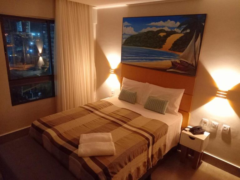 Habitación doble con cama matrimonial y vista nocturna a la ciudad en Ilusion Flats Aconchego de Ponta Negra