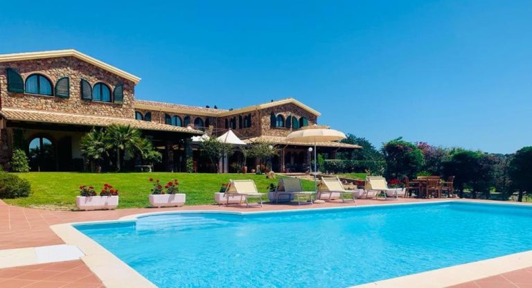 Piscina exterior con tumbonas y jardín del Hotel Janas, villa de piedra con arquitectura mediterránea