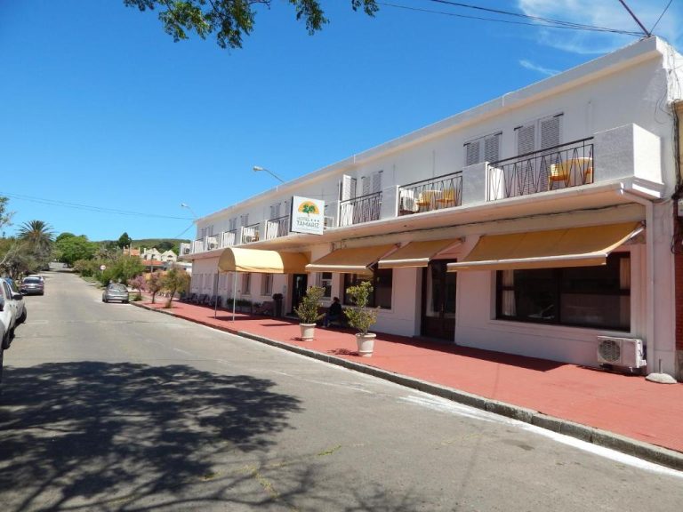Fachada exterior del Hotel Tamariz con toldos amarillos, terraza y balcones en día soleado