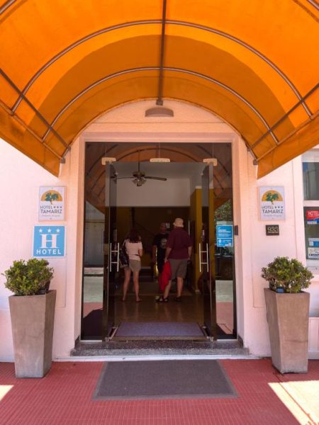 Entrada principal del Hotel Tamariz con marquesina naranja y puerta de acceso al lobby