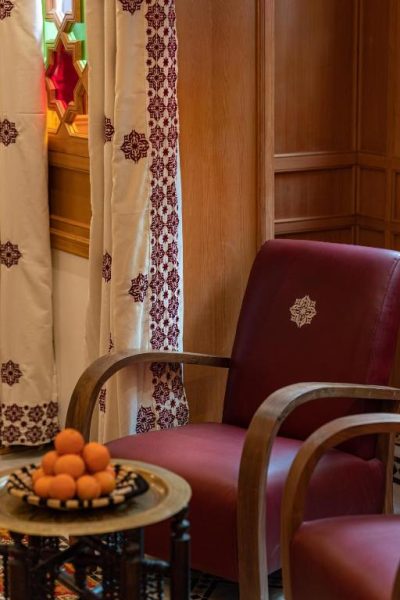 Sillón de cuero rojo con decoración arabesca y cortinas bordadas en La Maison Arabe Hotel Marrakech