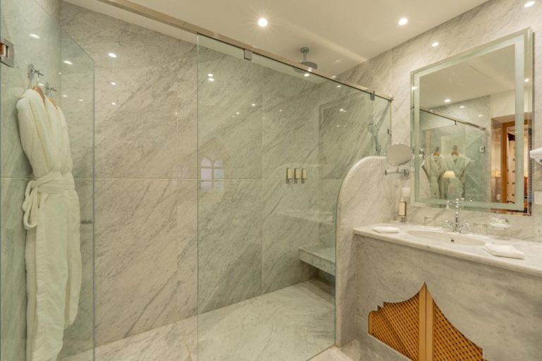 Baño de lujo con mármol blanco y ducha panorámica en La Maison Arabe Hotel Spa de Marrakech