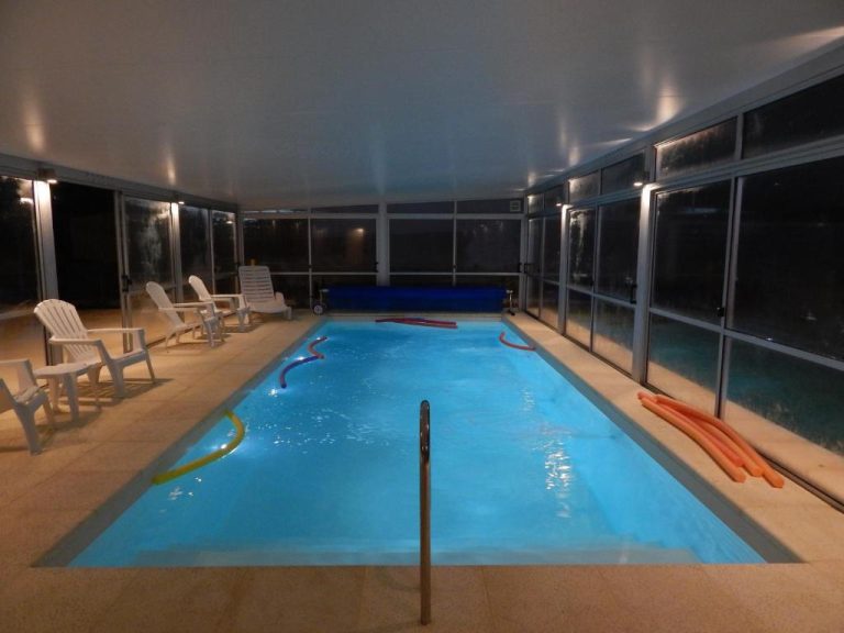 Piscina interior climatizada con flotadores del Hotel Tamariz, iluminada y rodeada de tumbonas blancas