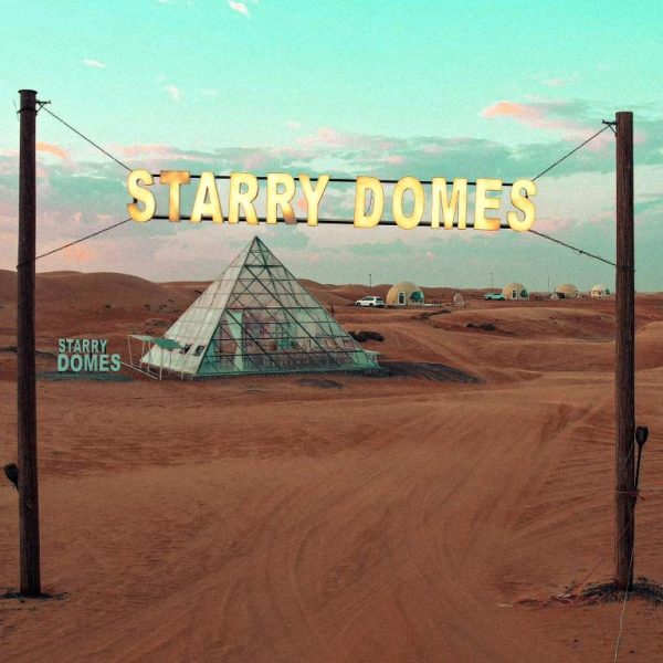 Entrada al Starry Domes Desert Camp con pirámide de cristal y domos en el desierto de arena
