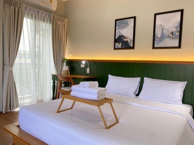 Habitación doble con cabecero verde y ropa de cama blanca en Alleyhill Phuket Boutique Hotel