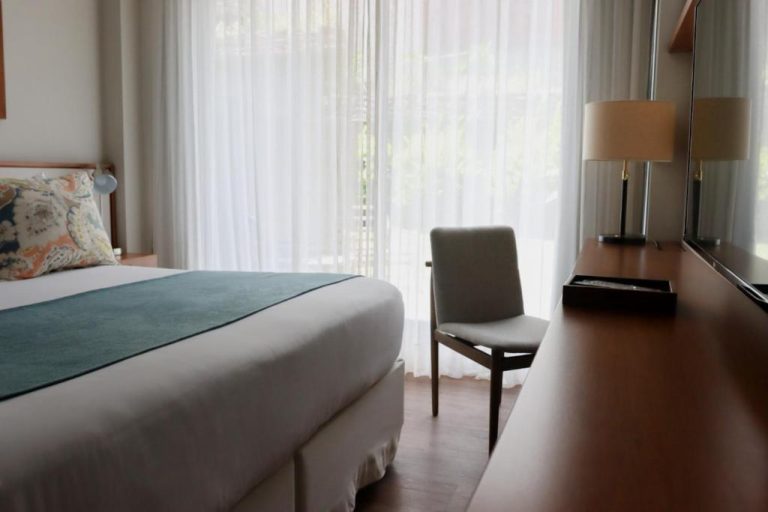 Habitación doble con cama, escritorio de madera y silla en Cottage Puerto Buceo