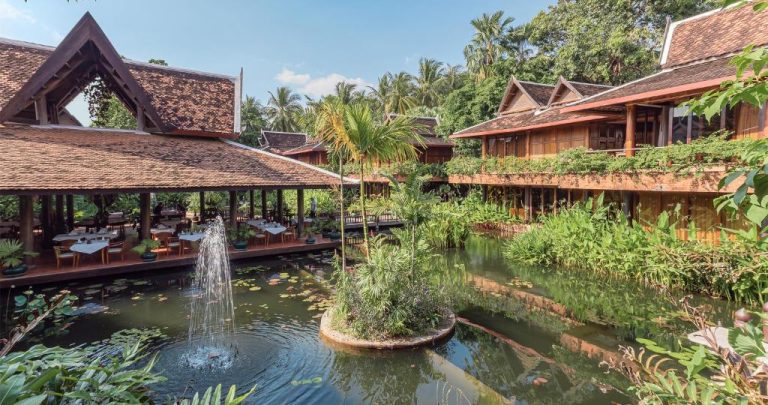 Restaurante exterior con fuente y estanque rodeado de vegetación tropical en Angkor Village Hotel Camboya
