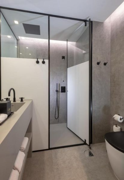 Baño moderno con ducha de lluvia y griferías negras en el Hotel Cajú