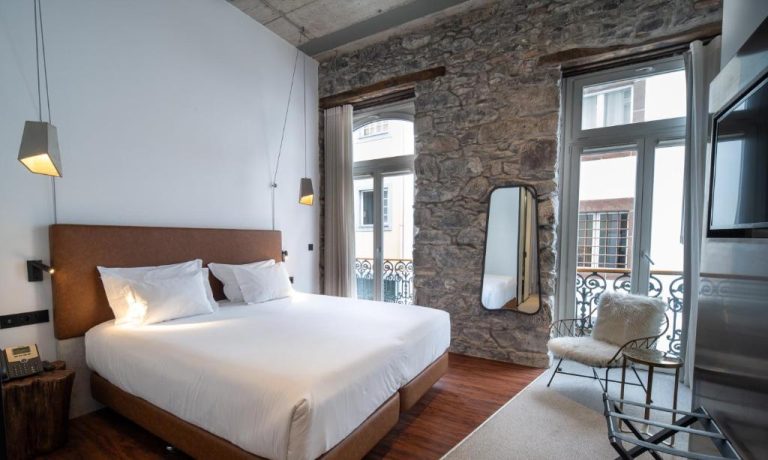 Habitación doble con pared de piedra natural y balcón en Hotel Cajú