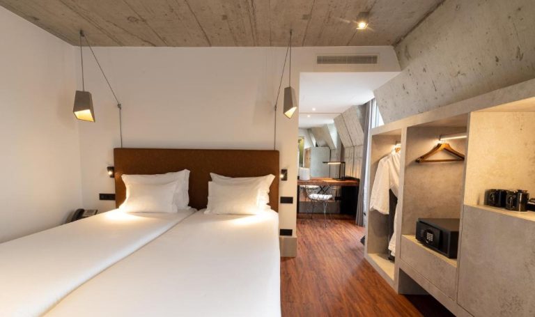 Habitación doble con diseño industrial y techo de hormigón en el Hotel Cajú