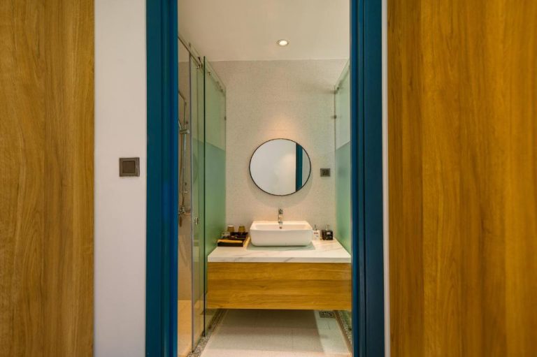 Baño moderno con lavabo sobre encimera y espejo redondo en Cat Loi Phu Quoc Hotel