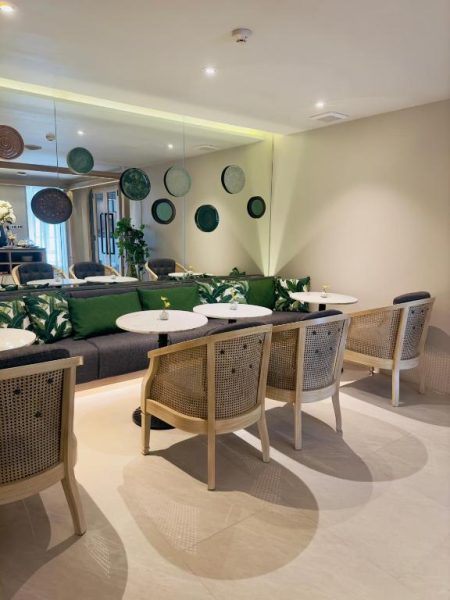 Salón restaurante elegante con sofás verdes y sillas de ratán en Maladee Rendezvous Hotel Chiang Mai