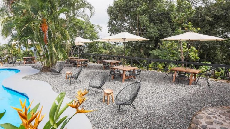 Terraza con mesas, sillas y sombrillas junto a la piscina exterior del Buen Camino Hotel en San Mateo