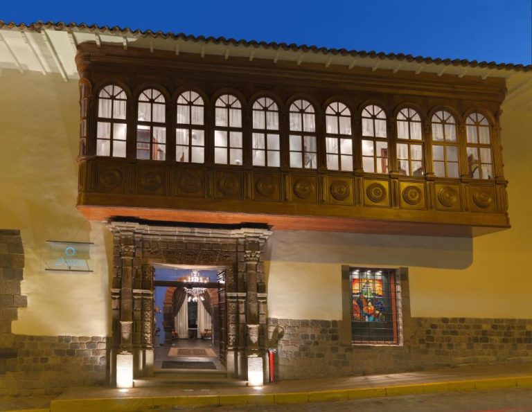 Fachada colonial con balcón de madera tallada e ingreso iluminado del Aranwa Cusco Boutique Hotel
