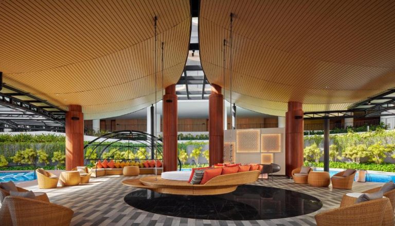 Lujoso lobby abierto con sofás de ratán y piscina exterior del PARKROYAL Langkawi Resort