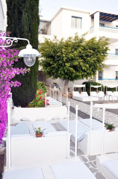 Zona de relax con tumbonas blancas y jardín con buganvillas en Tasmaria Aparthotel