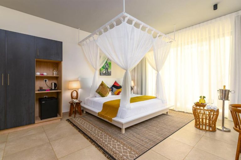 Habitación con cama de dosel y mosquitera blanca en TOA Hotel & Spa Zanzibar con decoración tropical