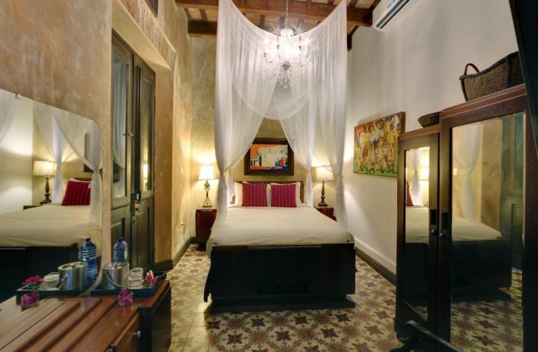 Habitación colonial con cama de dosel y lámparas cálidas en Villa Herencia Hotel