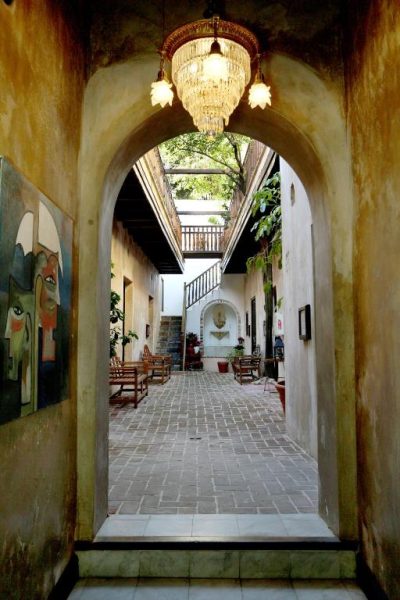 Patio interior con arco colonial y lámpara de cristal del Villa Herencia Hotel en San Juan