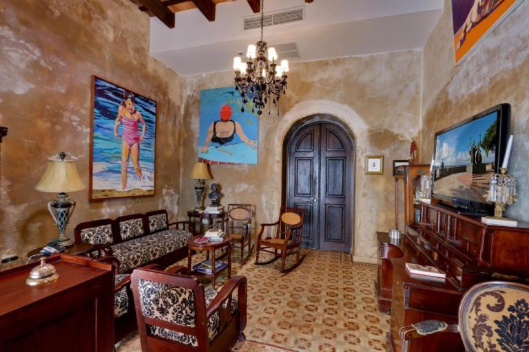 Elegante sala colonial con arte caribeño y muebles vintage en Villa Herencia Hotel en San Juan