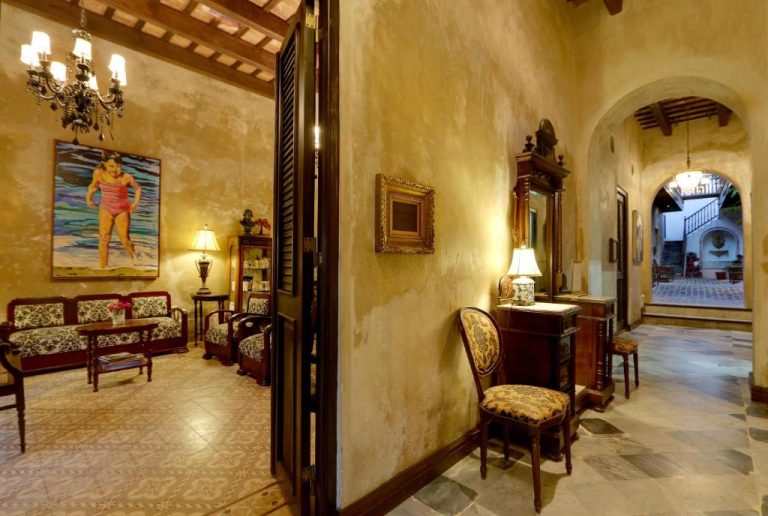 Recepción y pasillo colonial con decoración vintage y patio interior del Villa Herencia Hotel en Puerto Rico