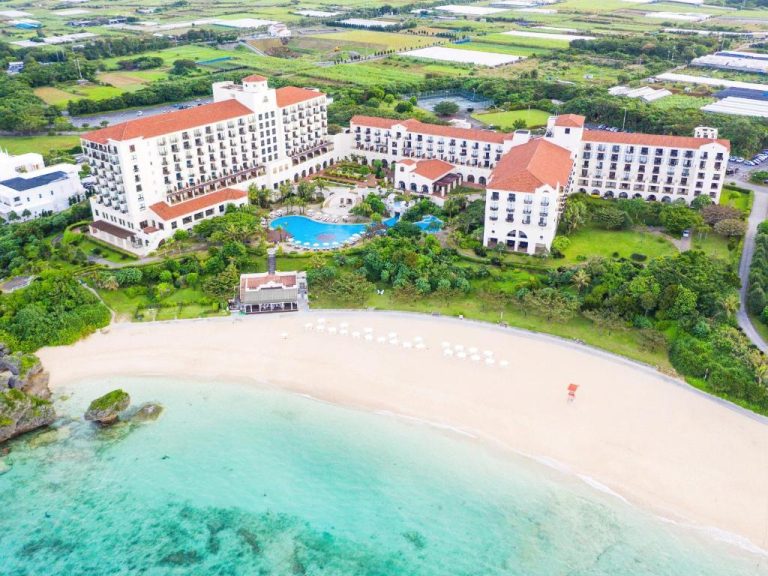 Vista aérea del Hotel Nikko Alivila con playa de arena blanca, piscina exterior y aguas turquesas de Okinawa