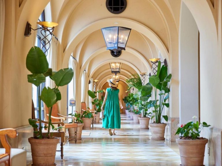 Corredor abovedado con plantas tropicales y mujer paseando en el Hotel Nikko Alivila